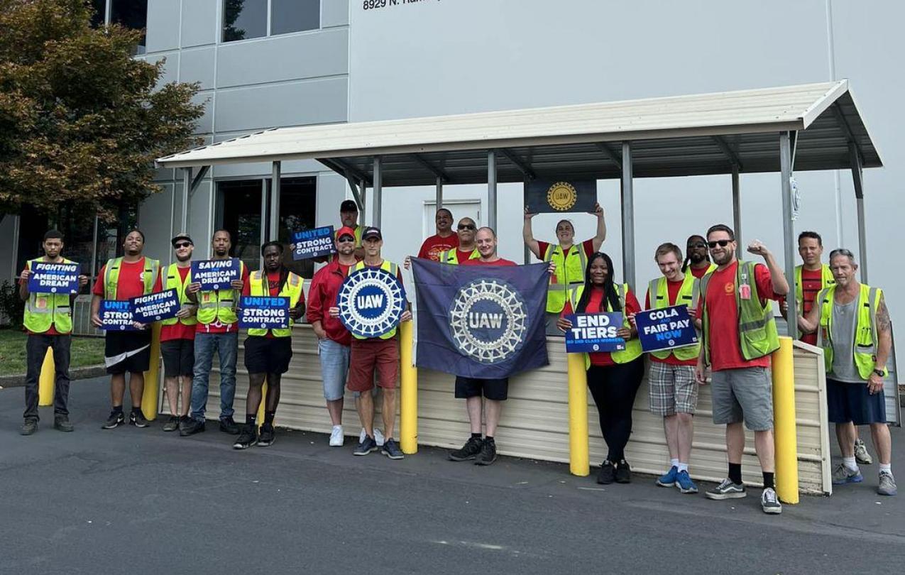 Members of UAW 492 standing outside with UAW posters and flags
