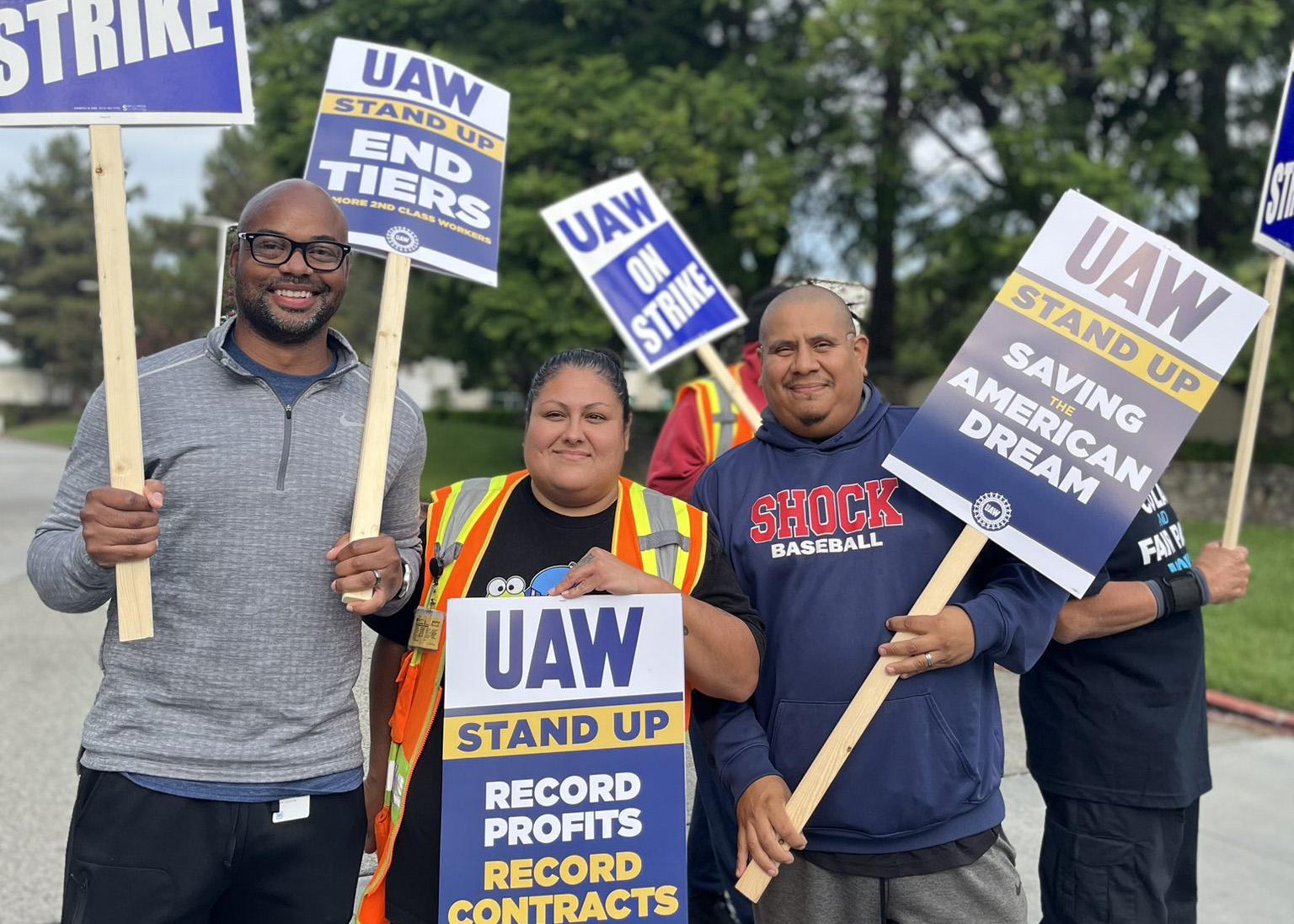 Three UAW 6645 members holding picket signs 