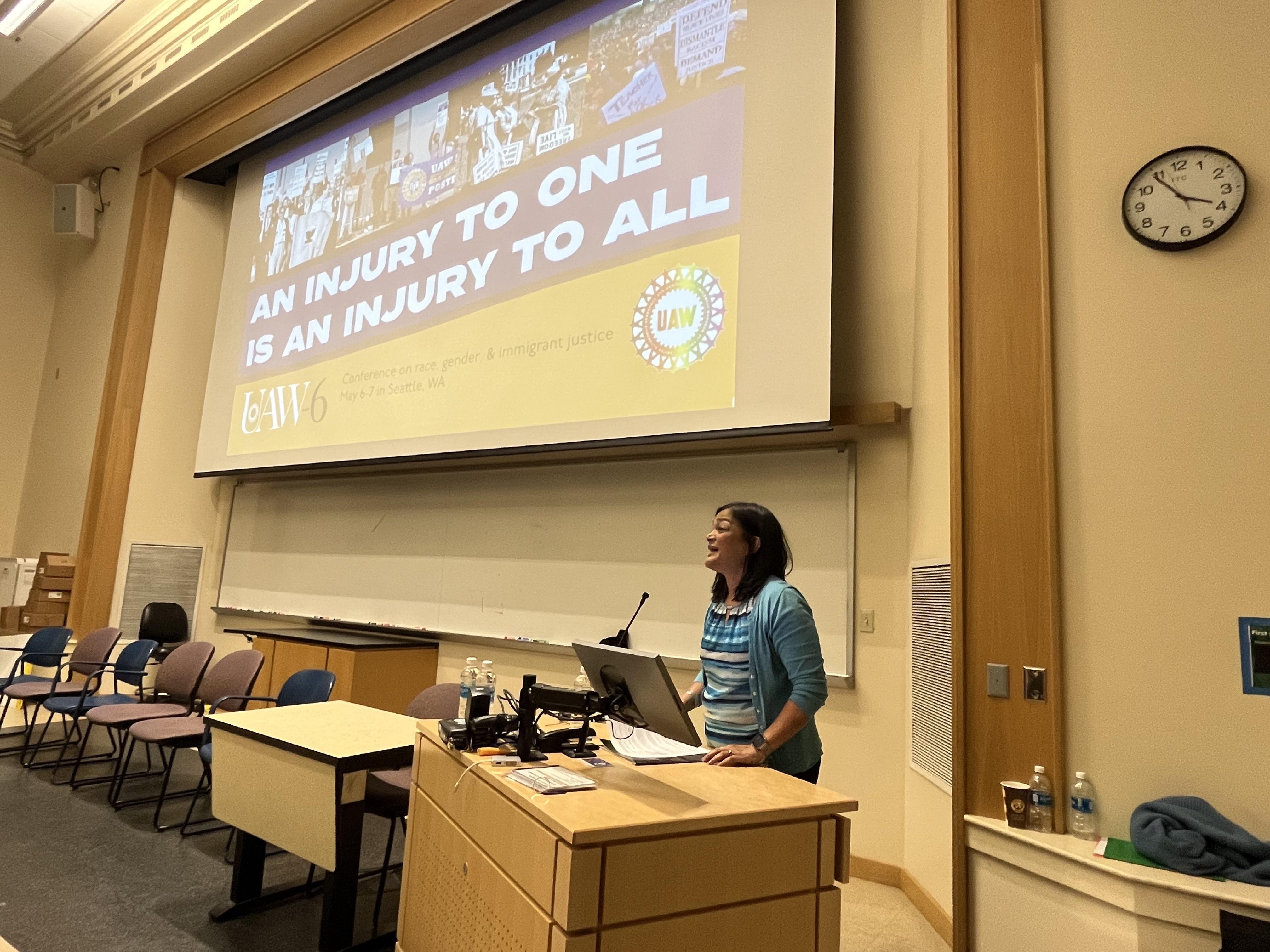 Pramila Jayapal standing at a podium and speaking to attendees at the conference