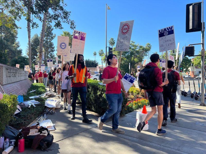 A line of about 30 USC grad workers marching with “last chance” practice picket signs 