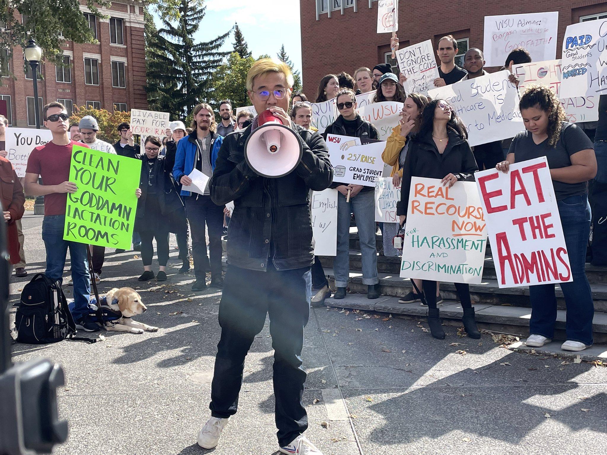 A member of WSU CASE holding a megaphone in front of a large crowd of Academic Student Employees holding signs  